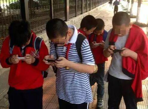 街头沉迷玩手机的小学生。